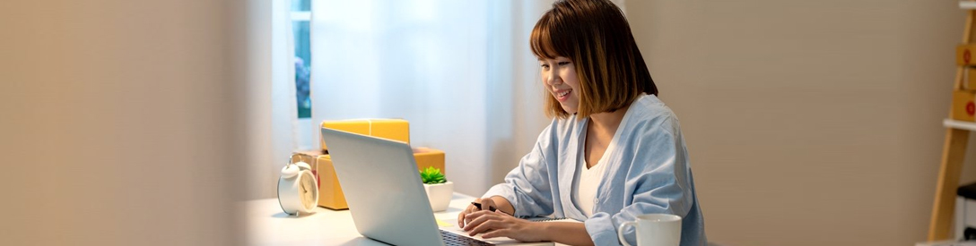 A woman typing on her laptop while smiling.