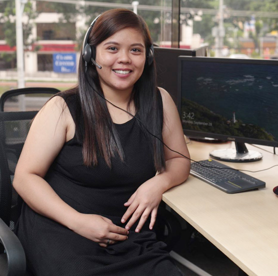 A Shore360, Inc, employee with a headset sitting at her desk smiling.