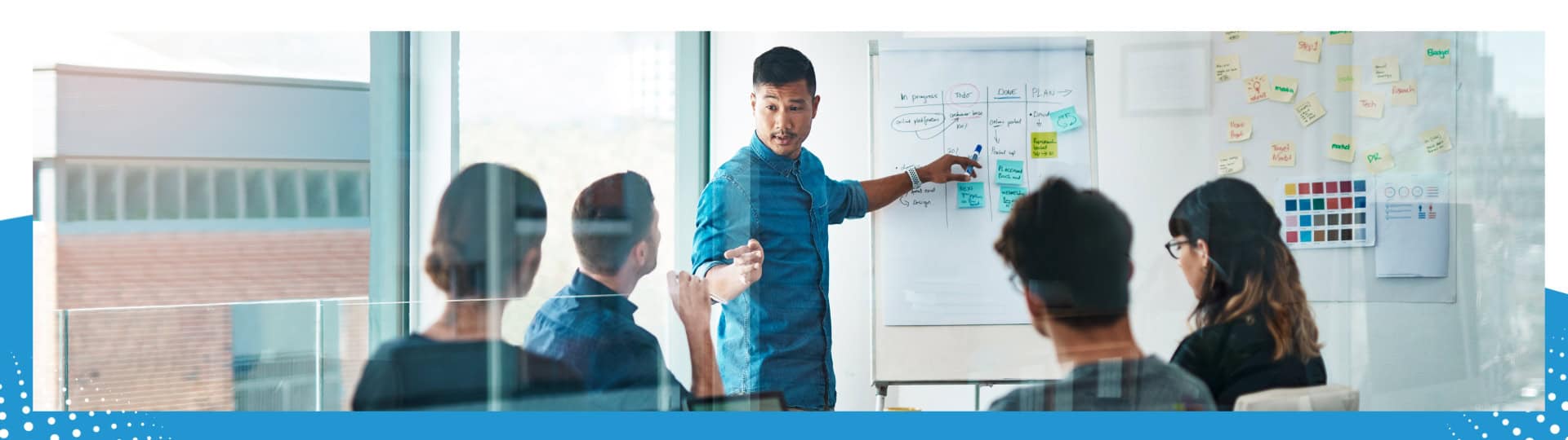 A team engaged in a brainstorming session, with a presenter pointing to a whiteboard filled with notes and diagrams, fostering collaboration and strategic planning.