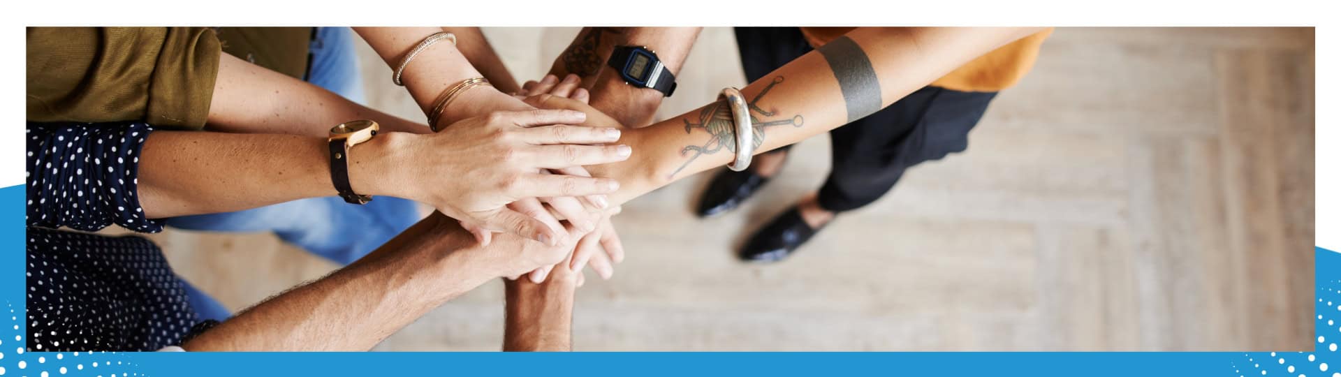 A group of diverse hands joined together in a stack, symbolizing teamwork, unity, and collaboration.