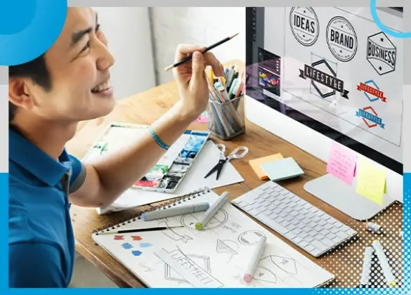 A Shore360 designer engaged in creating branding concepts on a computer, surrounded by design tools like markers, sketchbooks, and a vibrant digital workspace showcasing logo ideas.