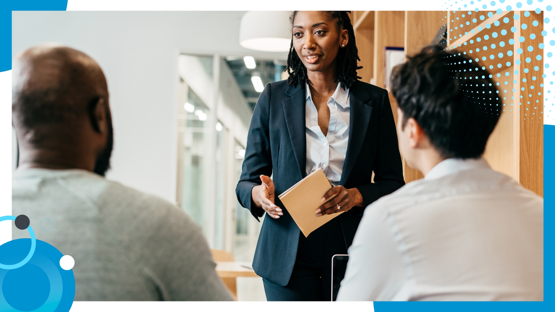 Confident businesswoman leading a discussion with two colleagues in a modern office setting.