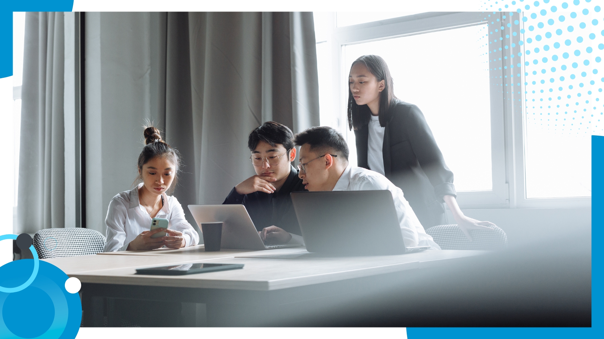 Focused group of young professionals collaborating on digital devices in a bright modern office