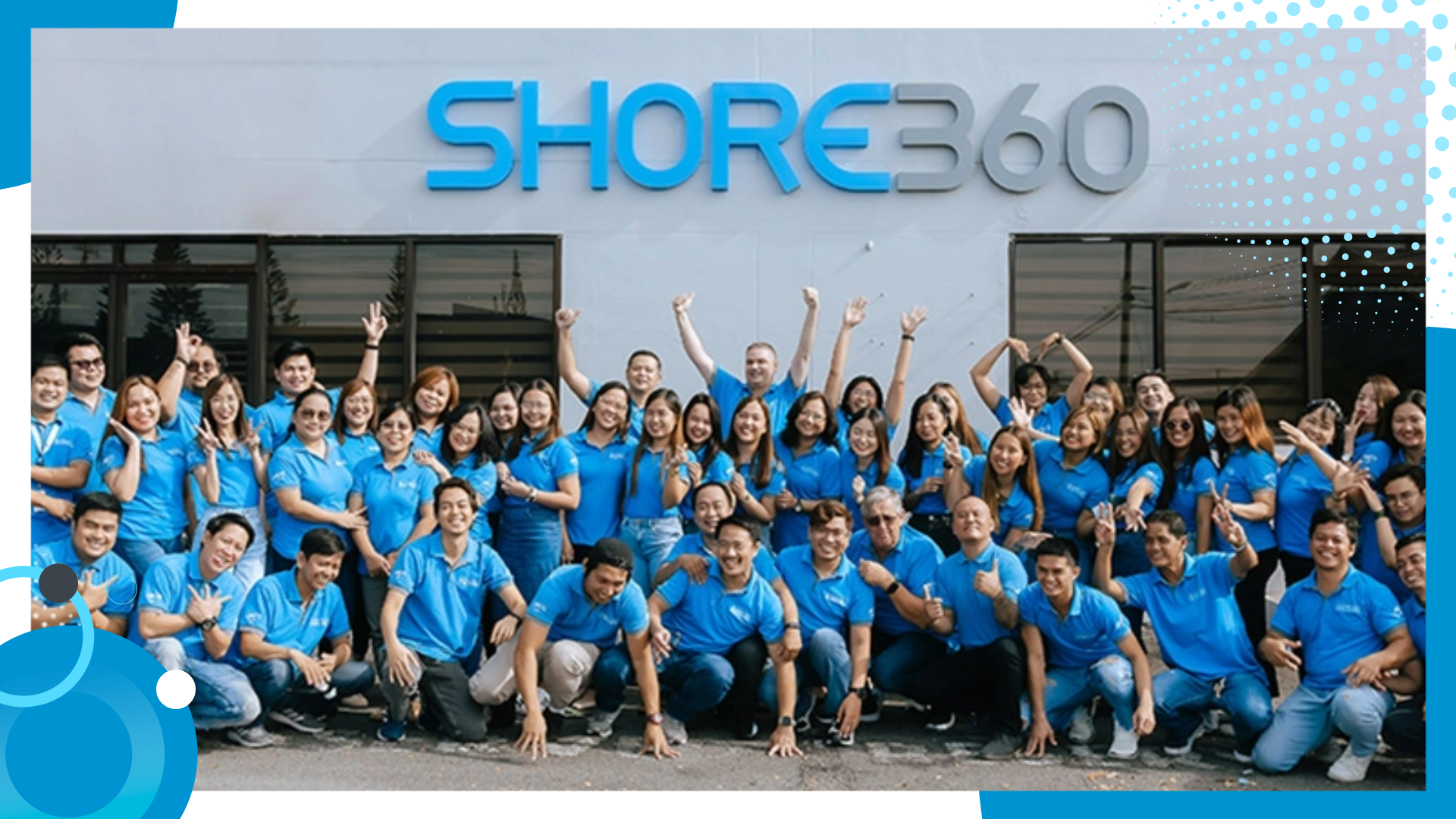 Group photo of Shore360 staff smiling and posing in front of the Shore360 office, all wearing branded blue uniforms.