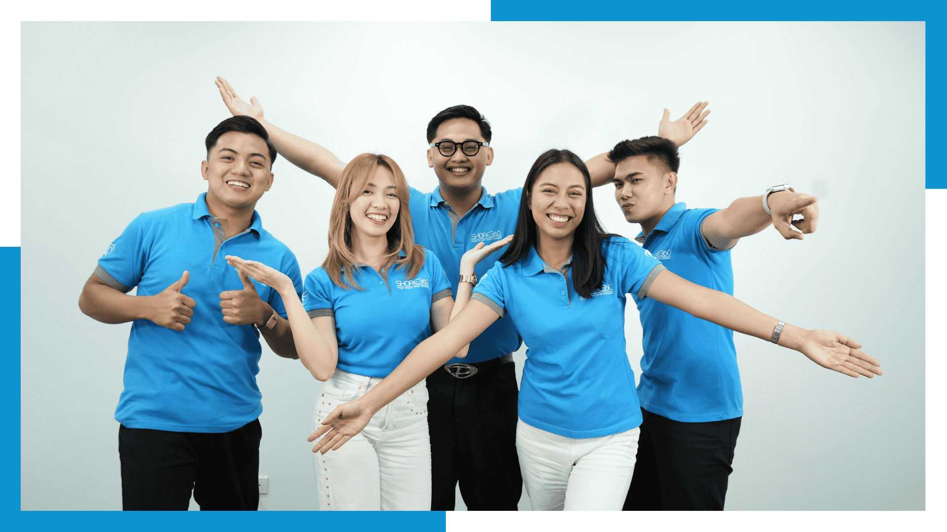 Shore360 team members in blue uniforms smiling and posing together, showcasing offshore outsourcing culture and teamwork.